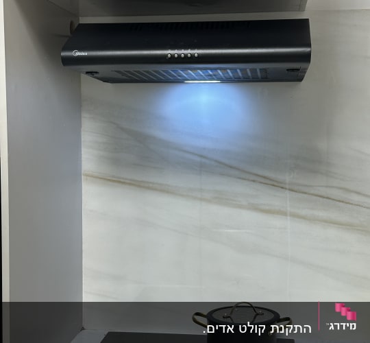 כיריים עם קולט אדים וסיר שחור במטבח